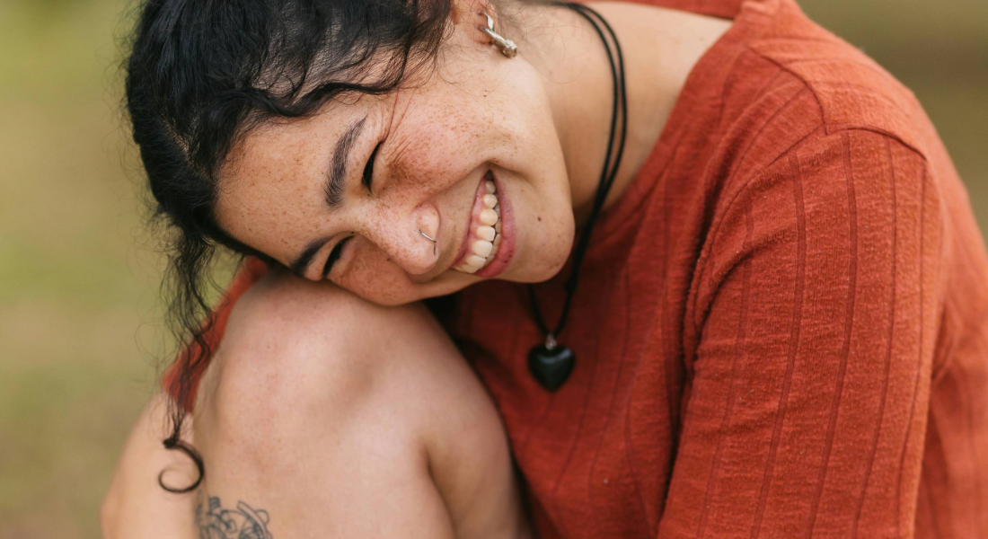 Smiling young woman sitting with her knee up and head down