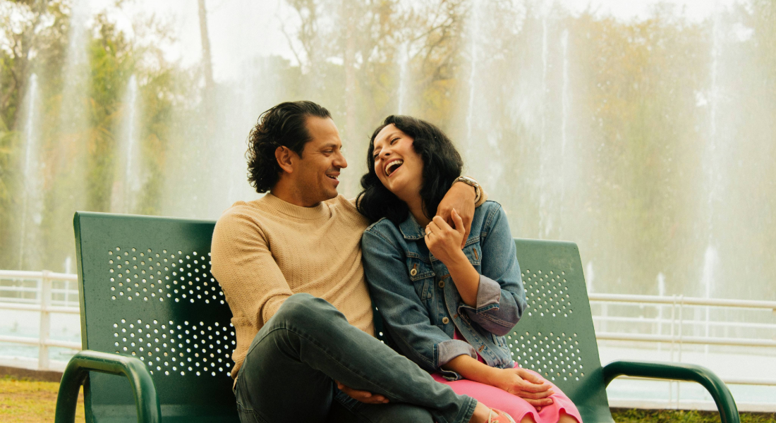 Men and woman on a bench together laughing
